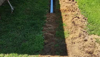 A pipe is being installed in the middle of a lush green lawn.