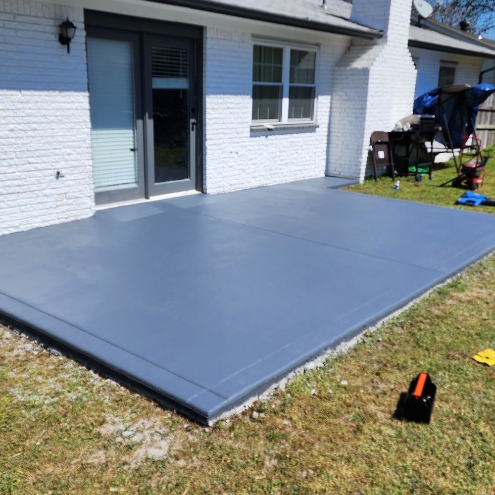 A gray concrete patio in front of a white brick house