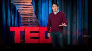 A man is standing on a stage in front of a ted talk sign.