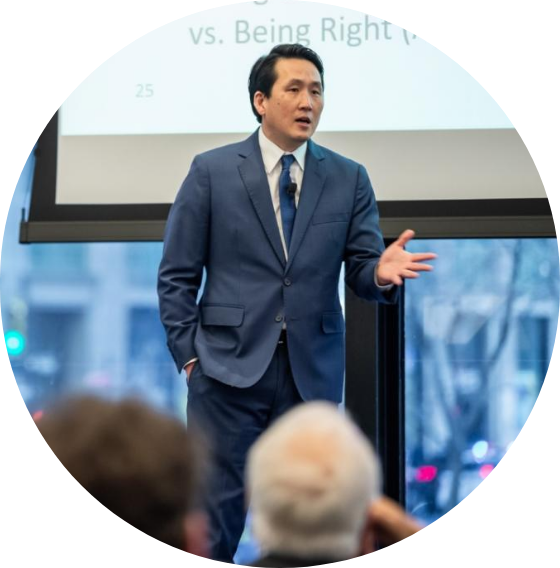 A man in a suit stands in front of a screen that says 