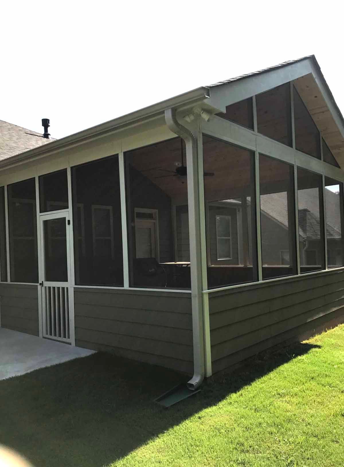 A screened in porch in the backyard of a house.