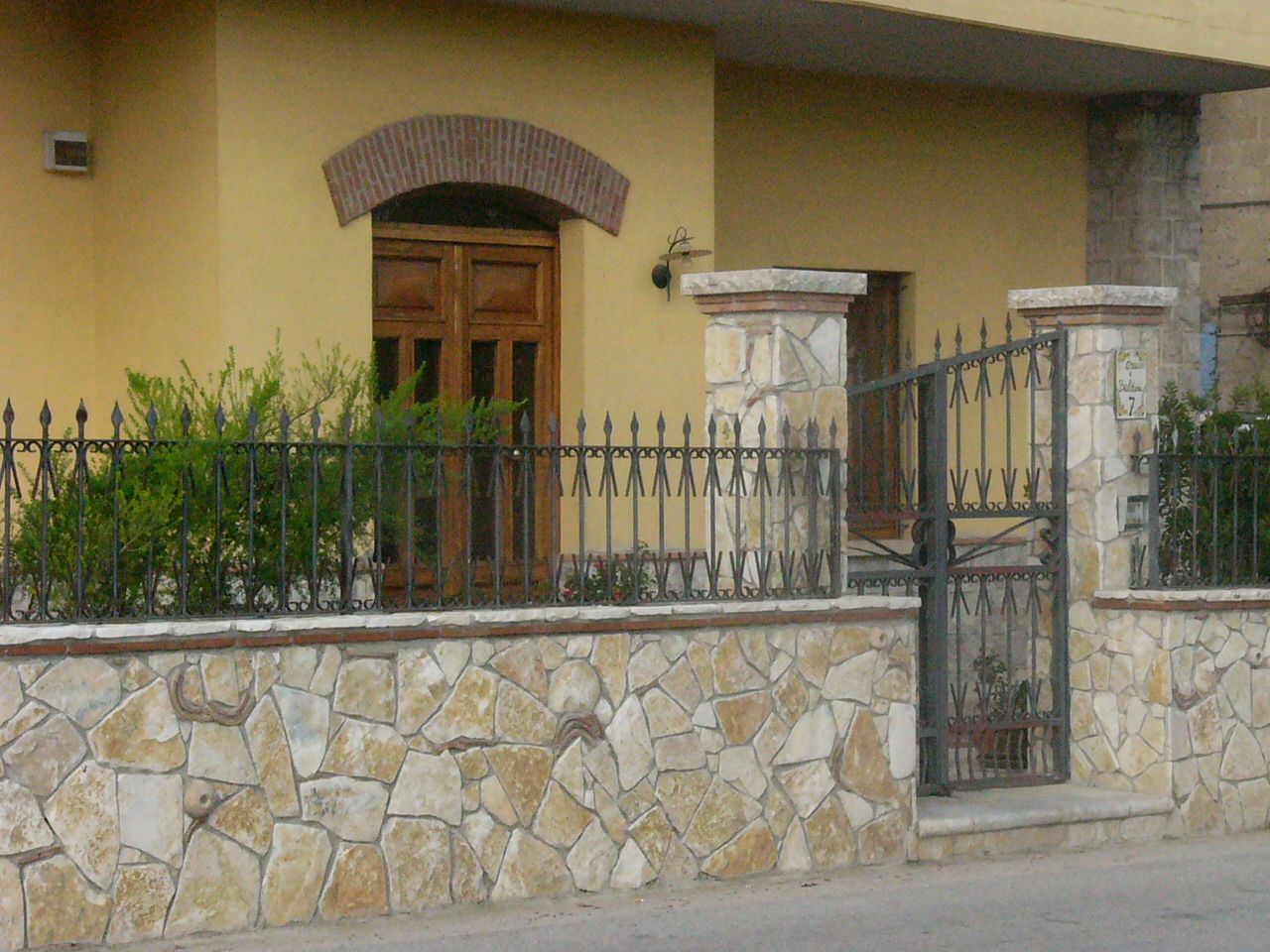 Una casa con un muro di pietra e un cancello in ferro battuto