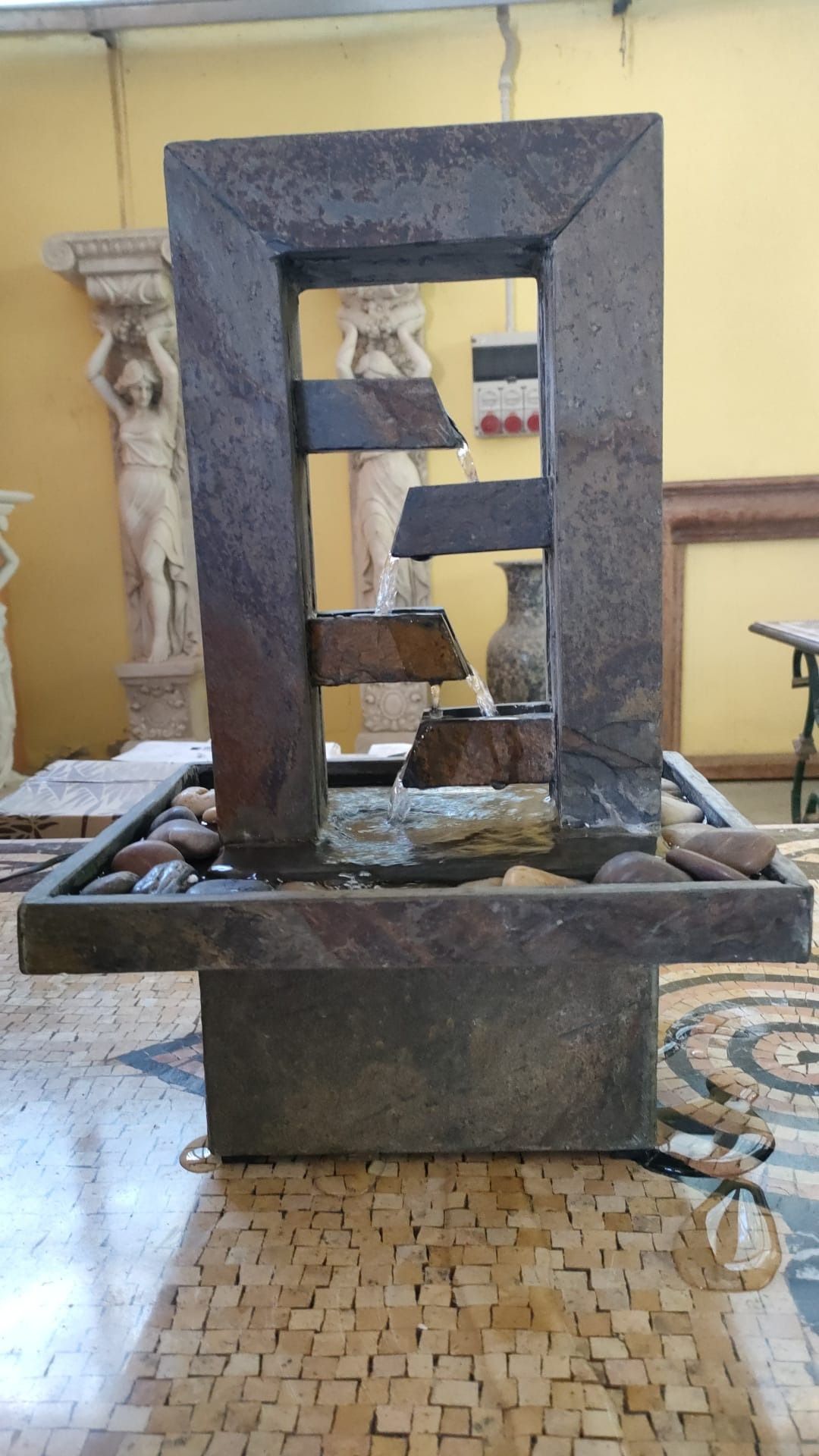 Una fontana d'acqua è posta su un pavimento piastrellato in una stanza.