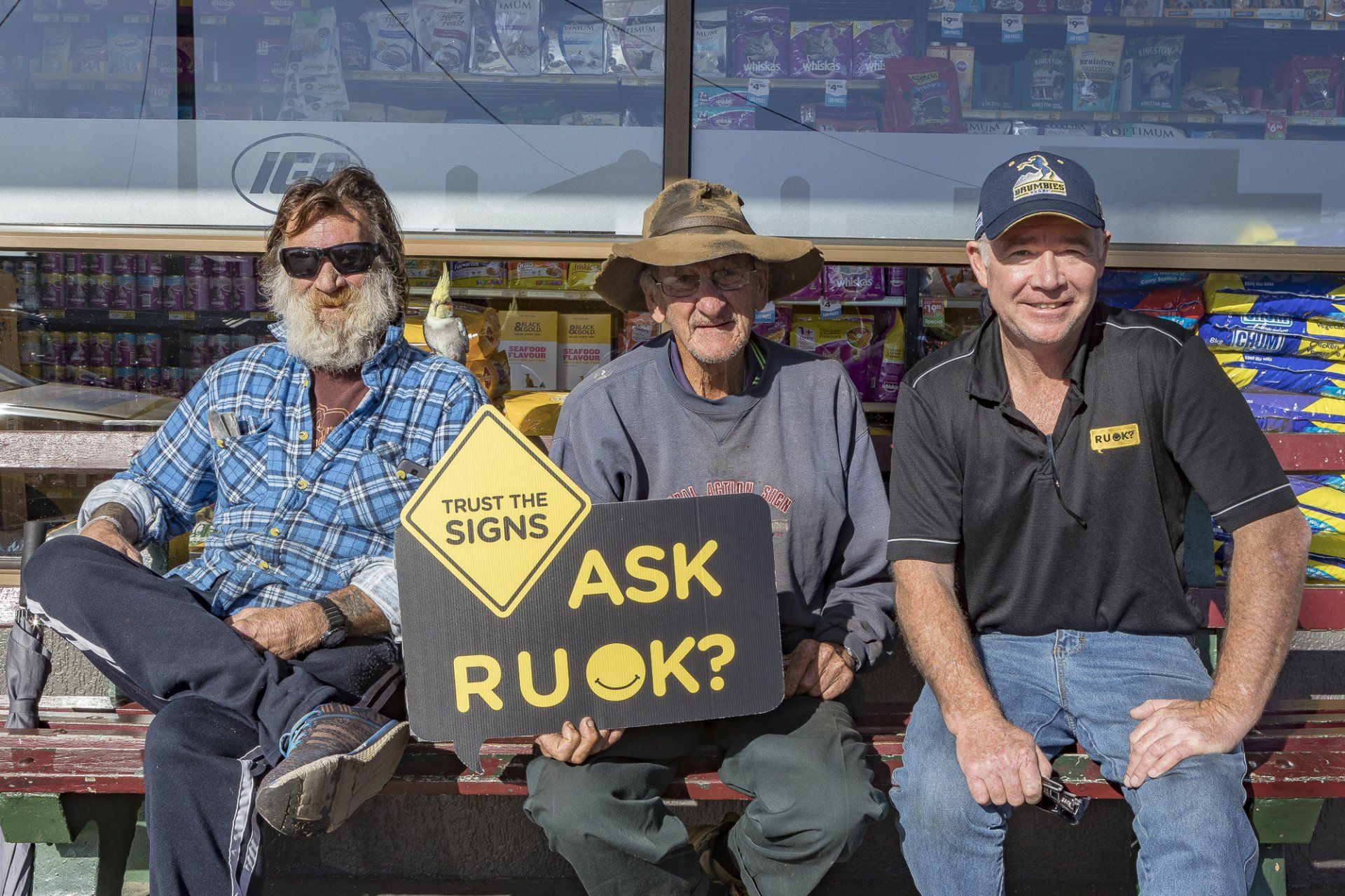 a group of mates sitting holding an R U OK? sign