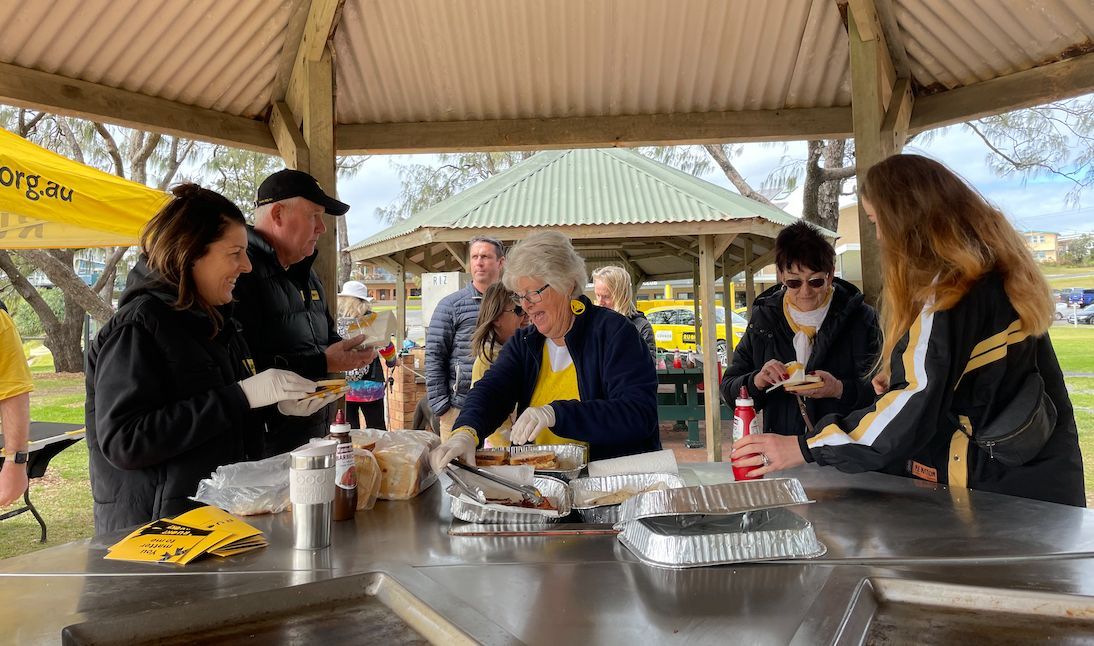 The Woolgoolga community enjoy a BBQ breakfast at the beach