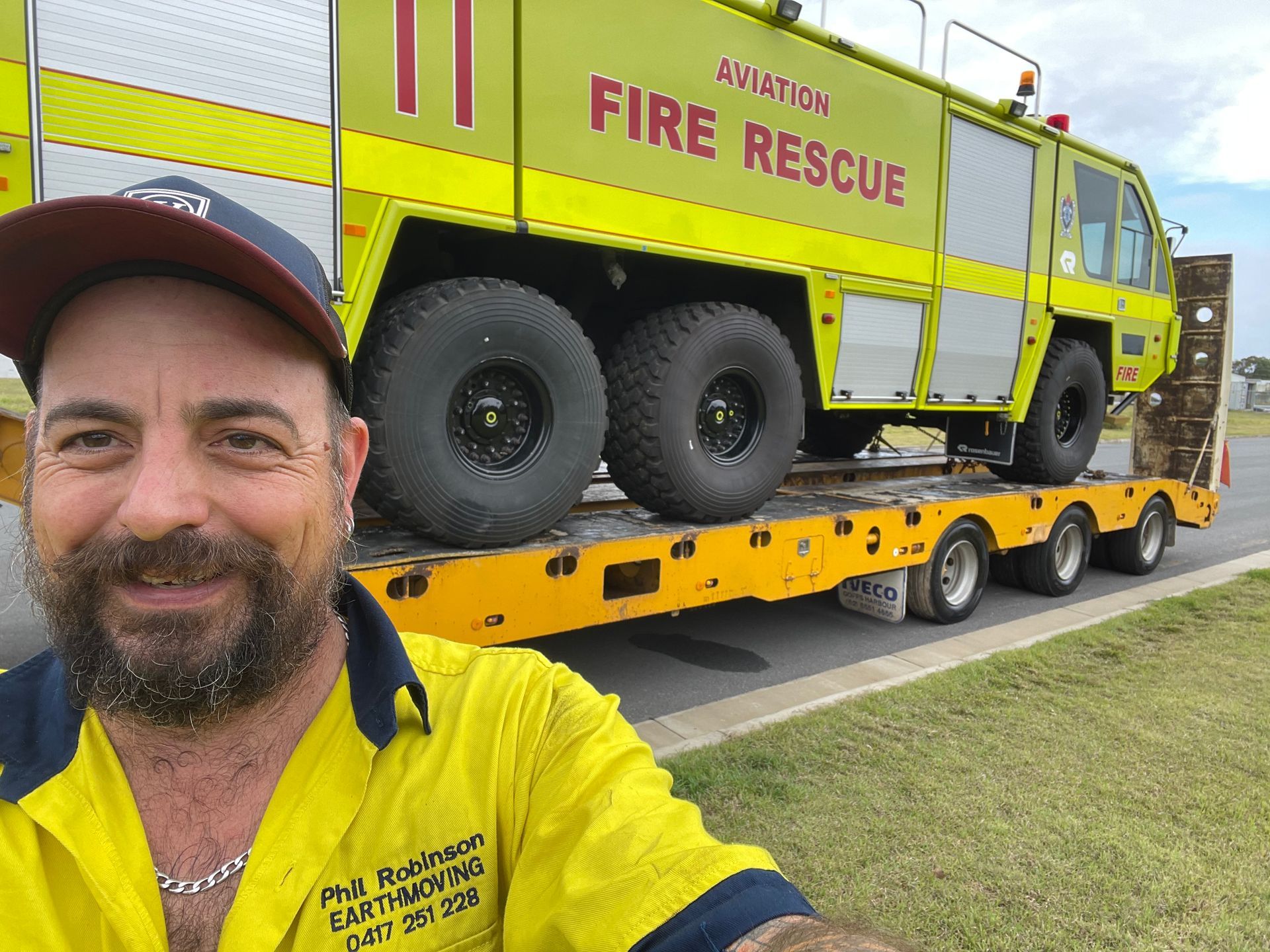 Truckie Eno poses in front of a yellow fire engine.