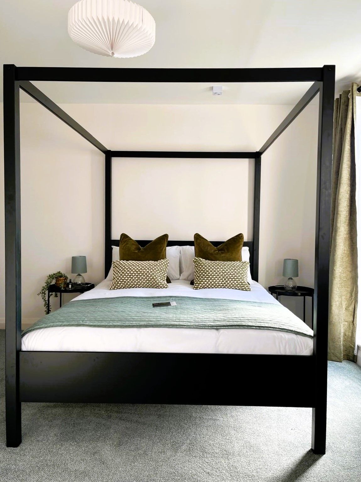 Modern bedroom with a black four-poster bed, patterned pillows, and light blue bedding.