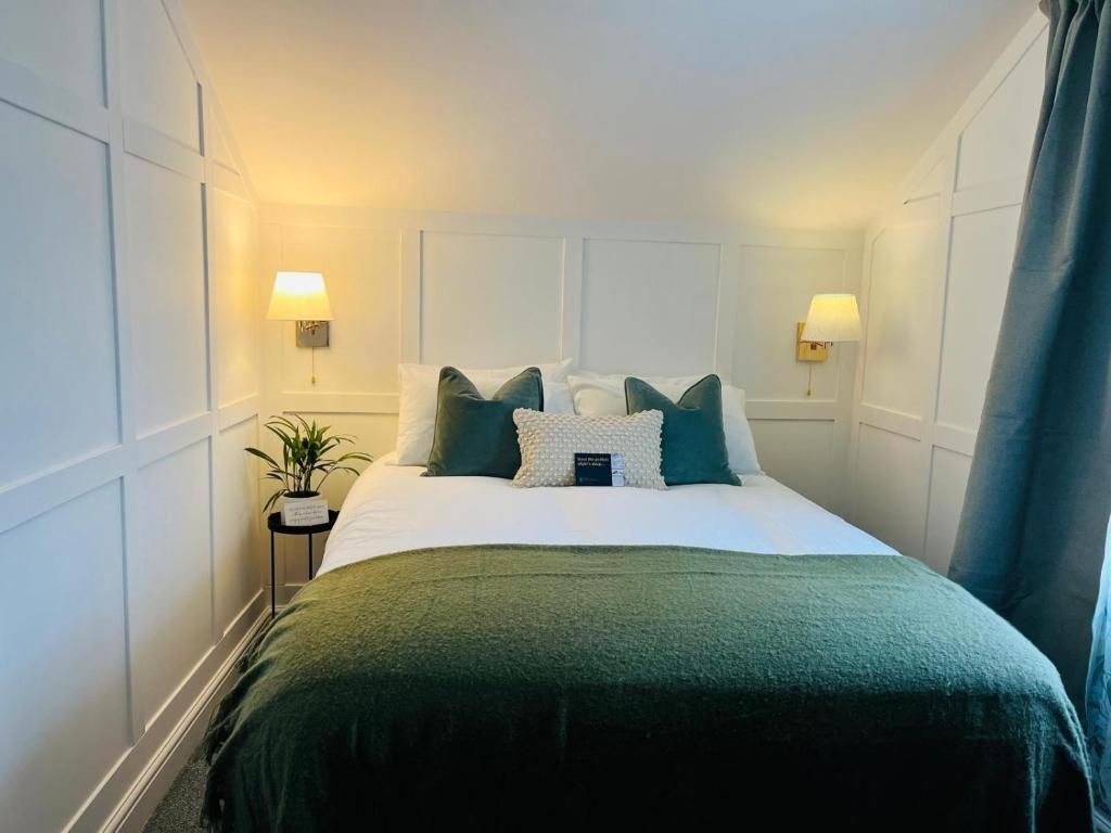Cozy bedroom with a green bedspread, white paneled walls, and warm bedside lamps