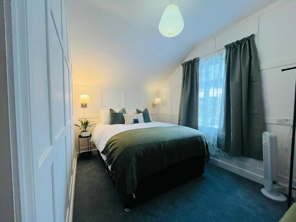 Cozy bedroom with a dark bedspread, white walls, blue curtains, and soft lamps by the bed