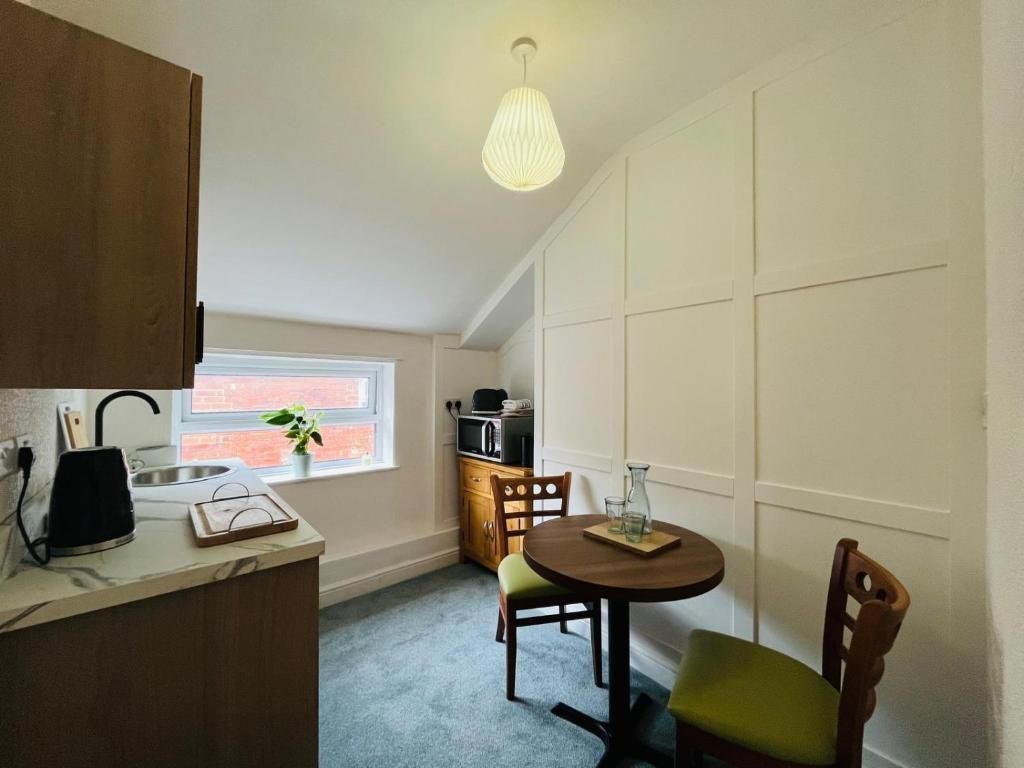 Small kitchen with wood cabinets, round table and chairs, white wall cabinets, and a window seat by a bright window