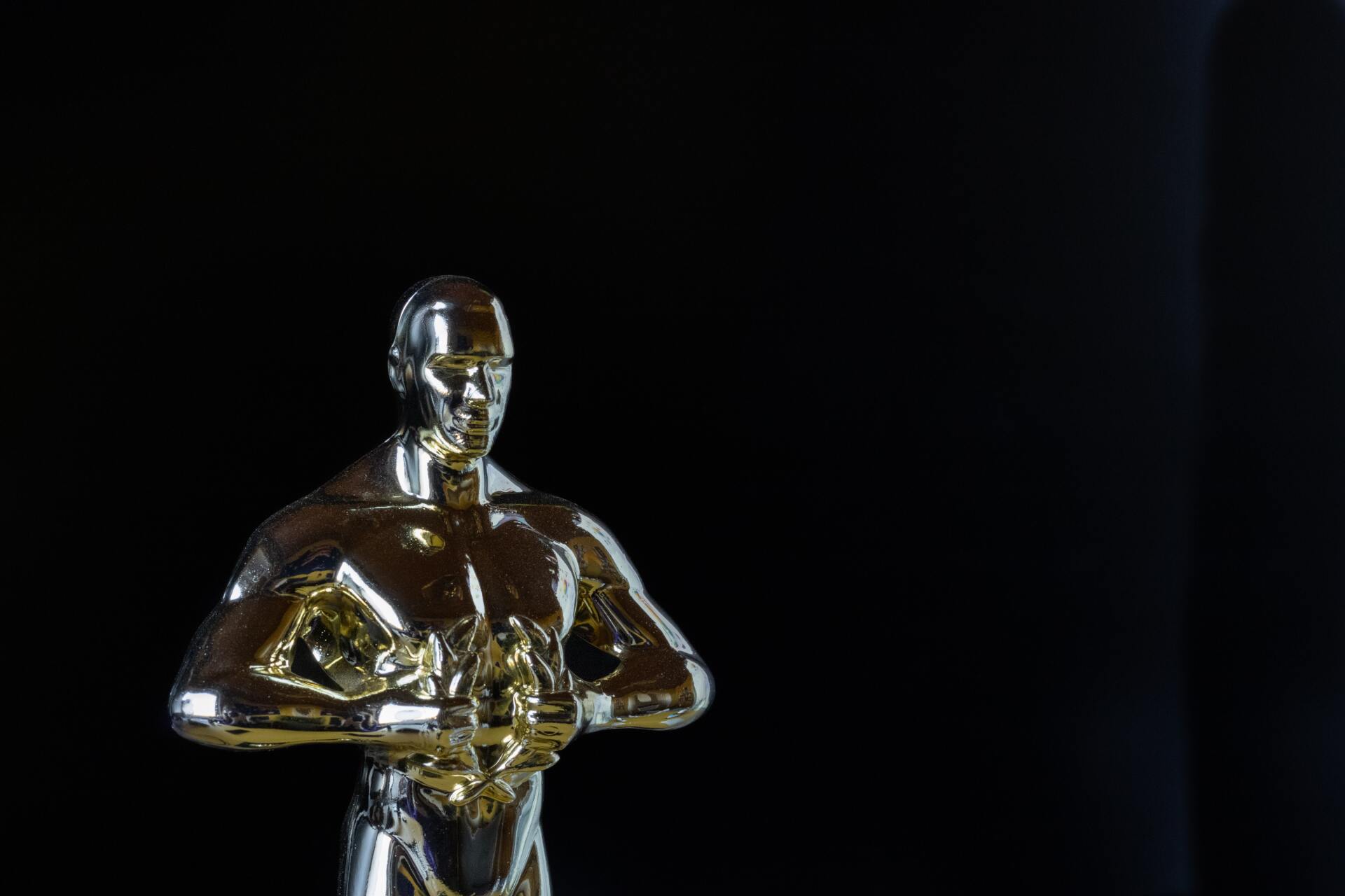 Golden Oscar statuette against a black background.