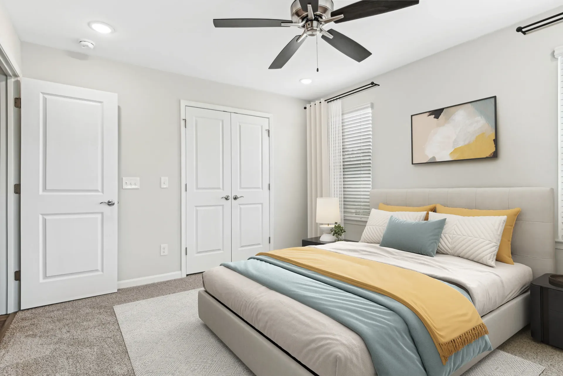 Bedroom in a modern apartment with a bed, ceiling fan, two closet doors, and a window.