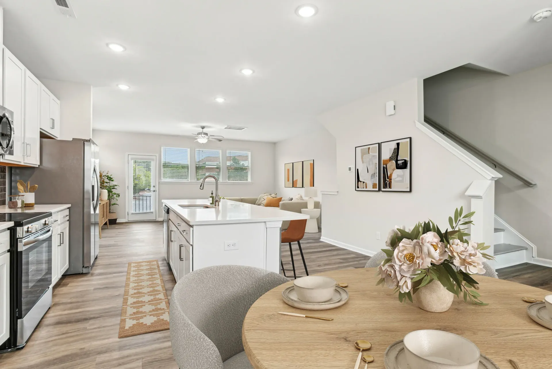 Open-concept kitchen and dining area with a large island, white cabinets, and stainless steel appliances.