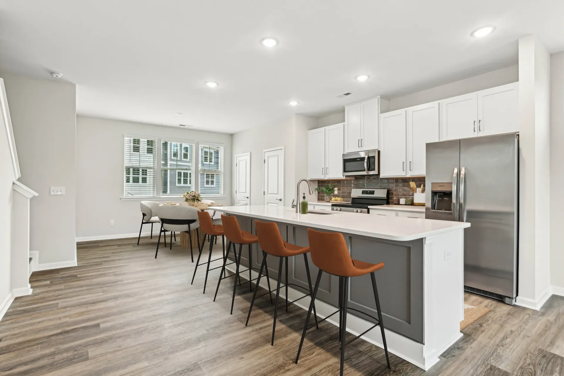 Open-concept kitchen in a modern apartment with a large island, white cabinets, and stainless steel appliances.