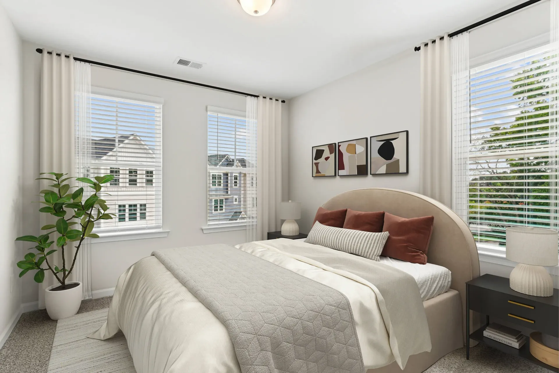 Bright bedroom with a curved headboard, neutral bedding, and large windows with white blinds.