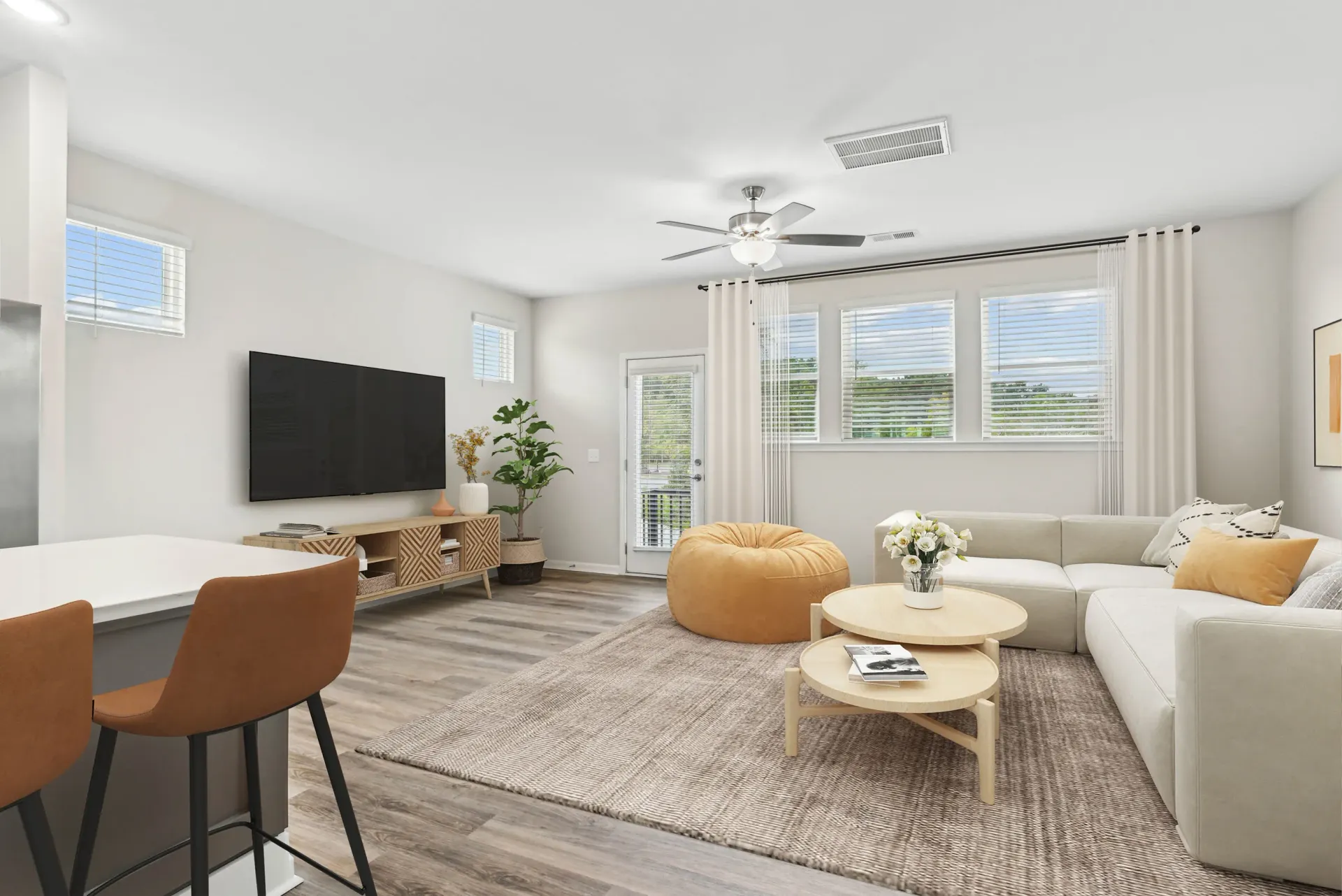 Bright living room in a modern apartment with a sofa, bean bag, TV, and large windows.