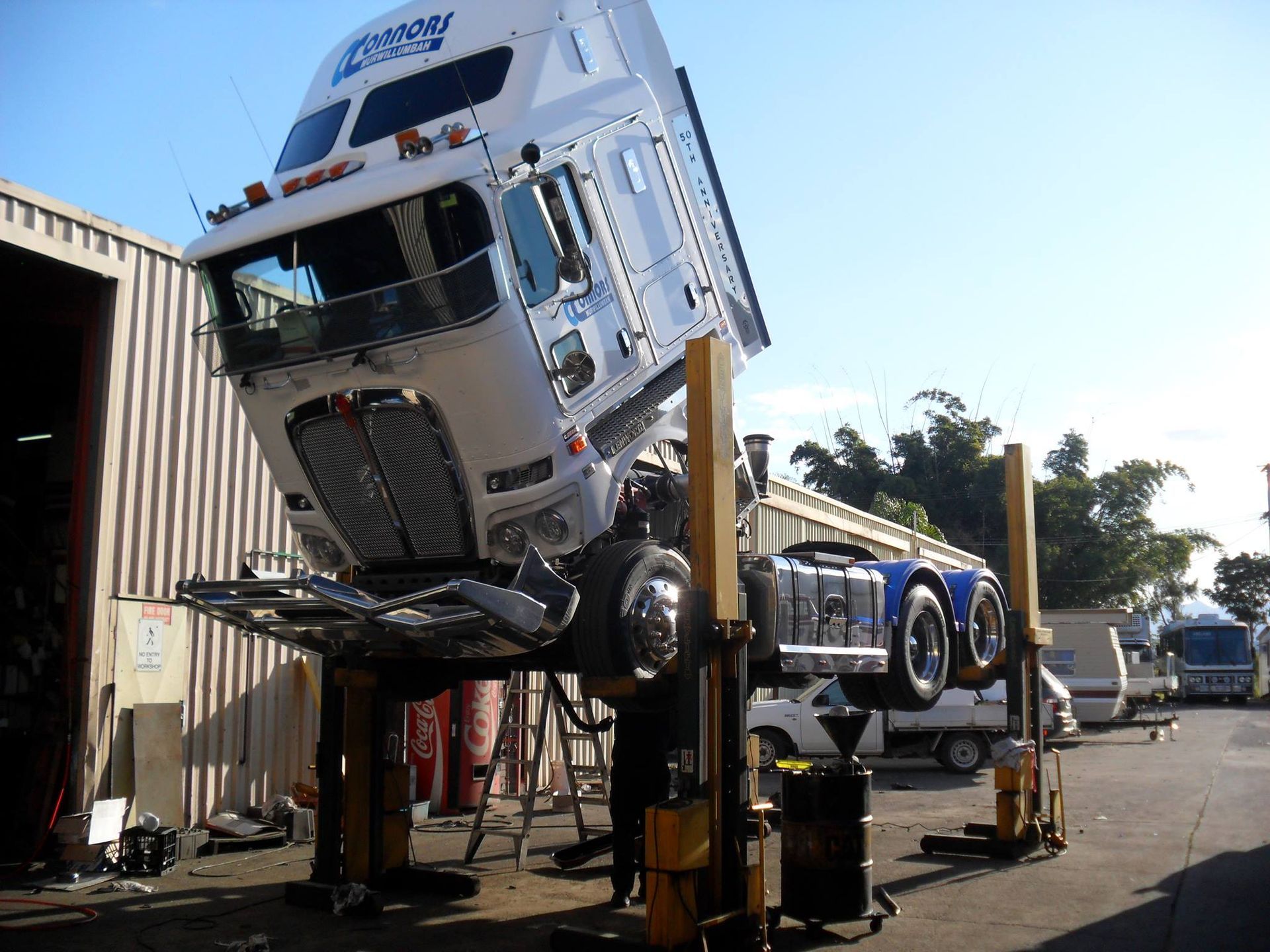 A white and blue truck up on lift — All Engine Repairs in South Murwillumbah, NSW