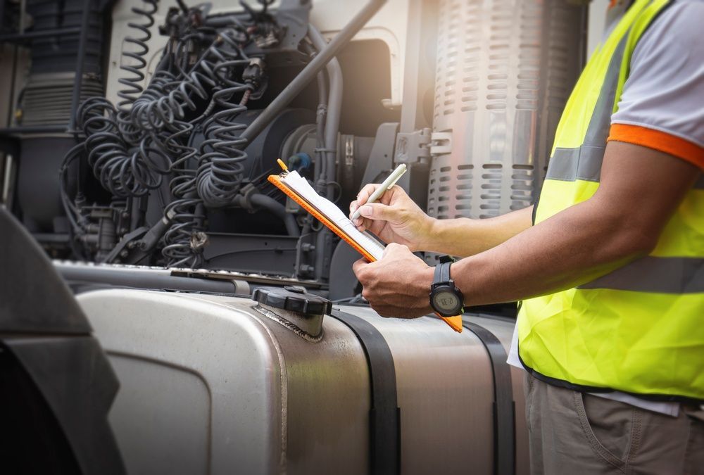 A Man Is Writing On A Clipboard While Standing Next To A Truck — All Engine Repairs in South Murwillumbah, NSW