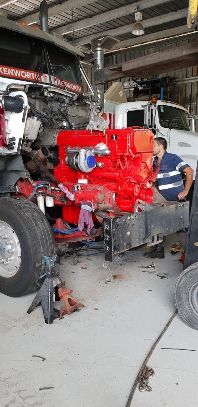 A Man Is Working On A Red Truck Engine In A Garage — All Engine Repairs in South Murwillumbah, NSW