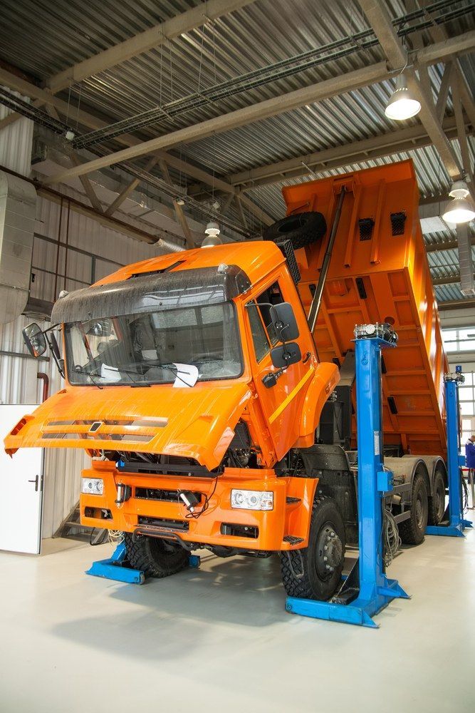 An Orange Dump Truck Is Sitting On A Lift In A Garage — All Engine Repairs in South Murwillumbah, NSW