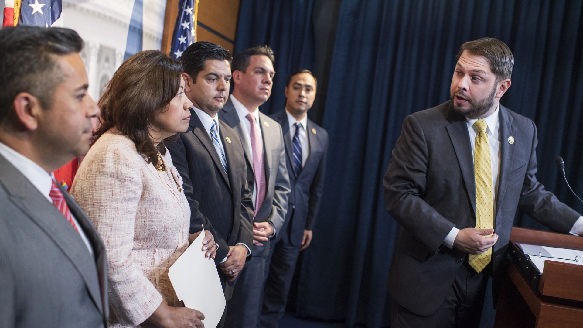 A group of people in suits and ties are standing around a podium.
