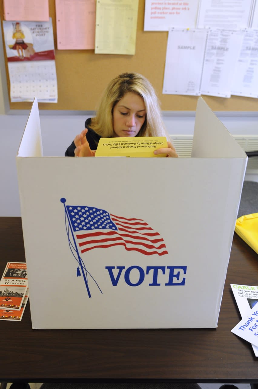 A woman sitting at a voting booth that says vote