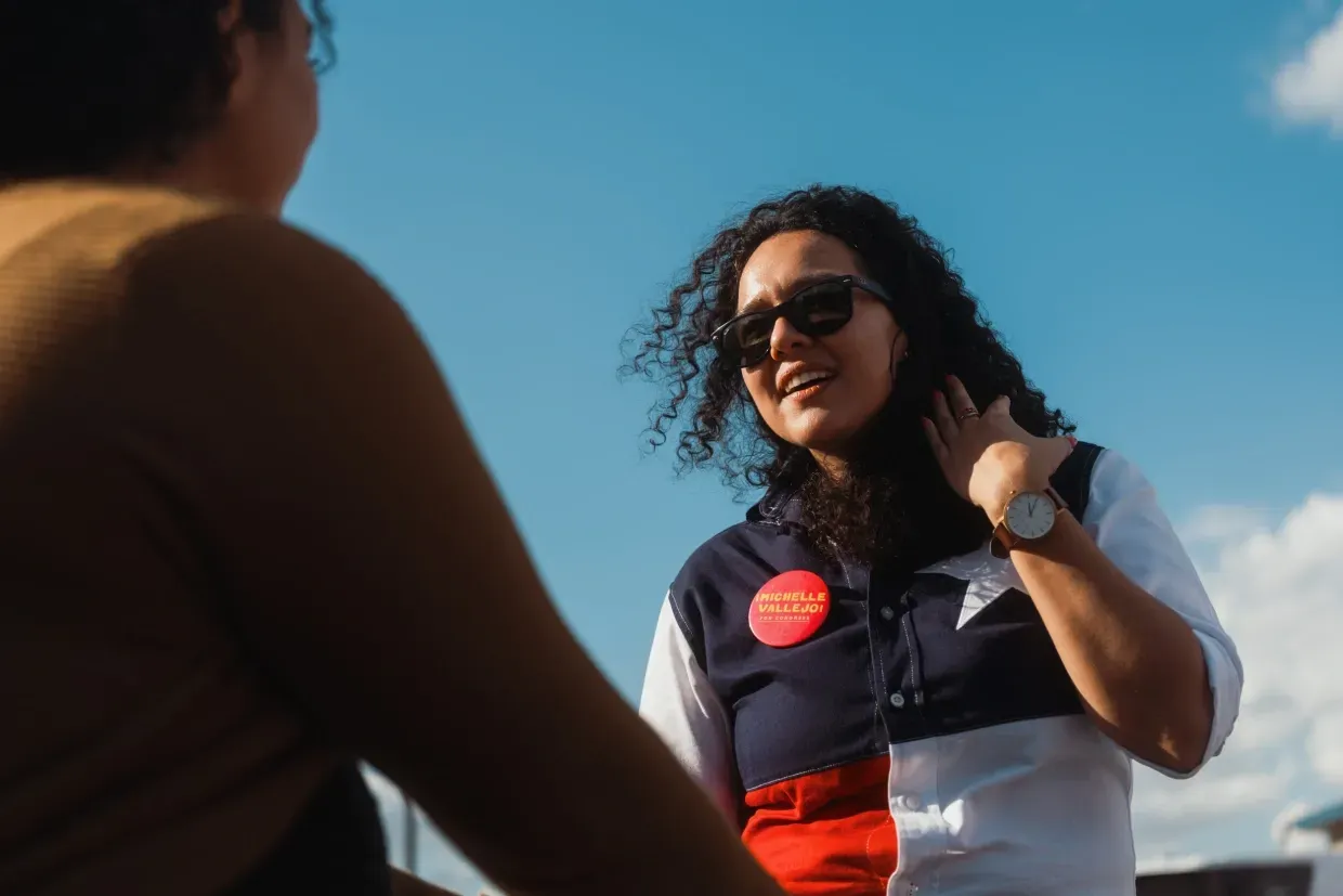 A woman wearing sunglasses is talking to another woman.