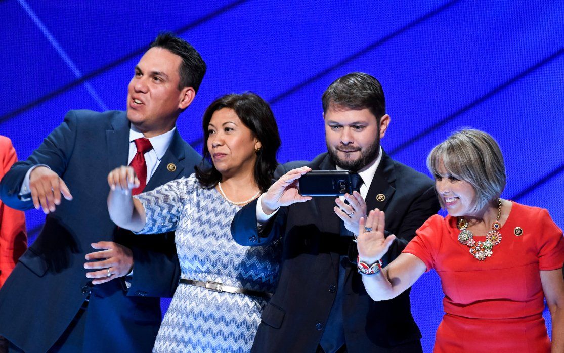 A group of people are taking a selfie on a stage.