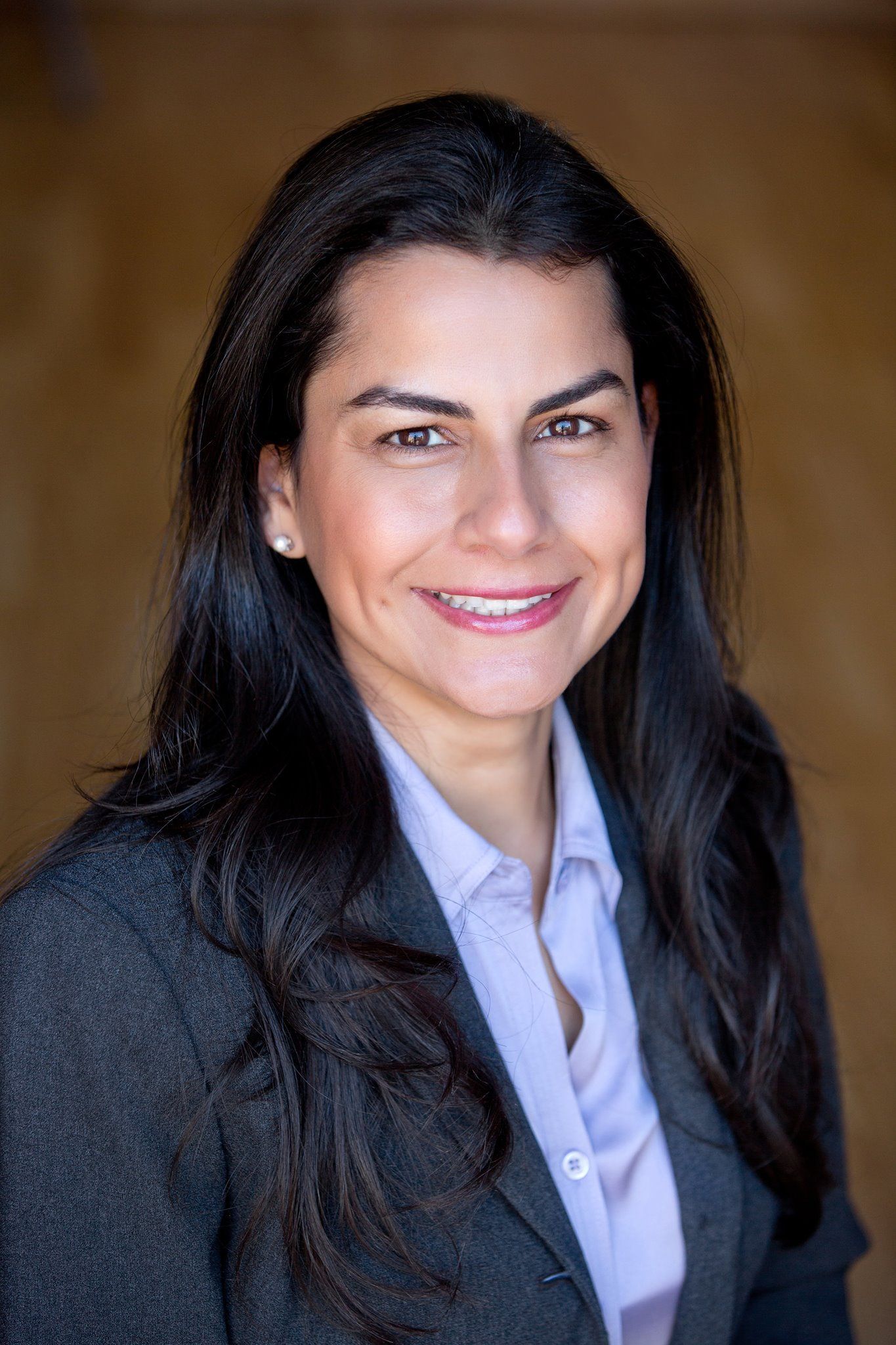 A woman in a suit and a purple shirt is smiling for the camera.