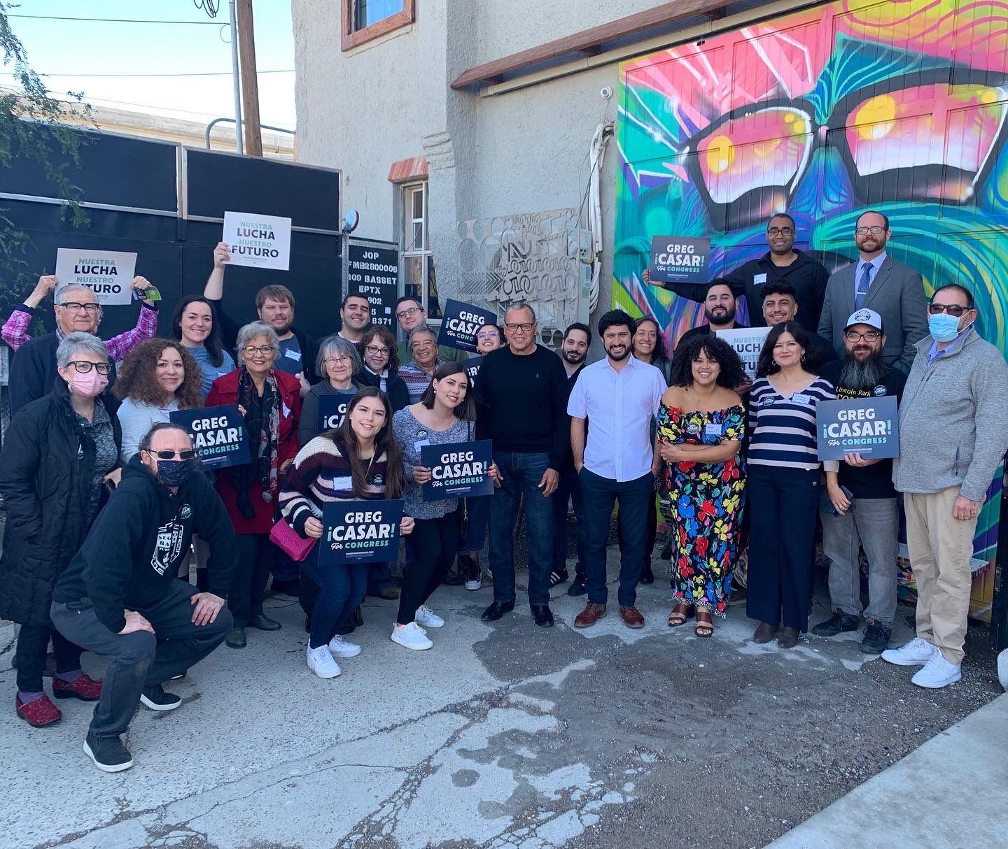 A group of people are posing for a picture in front of a mural.