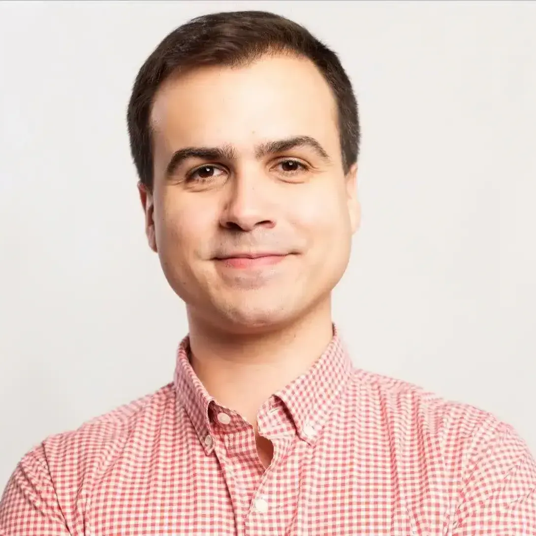Smiling man in a red checkered shirt against a light background