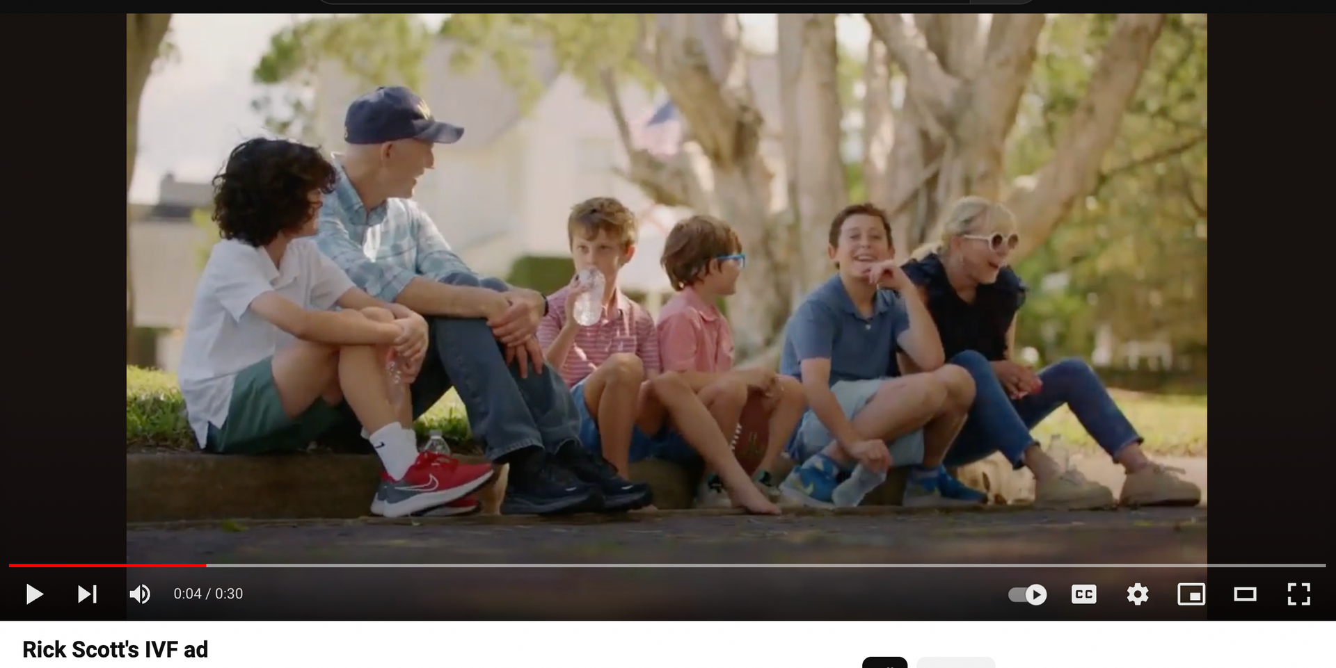 A group of people are sitting on the side of a road.