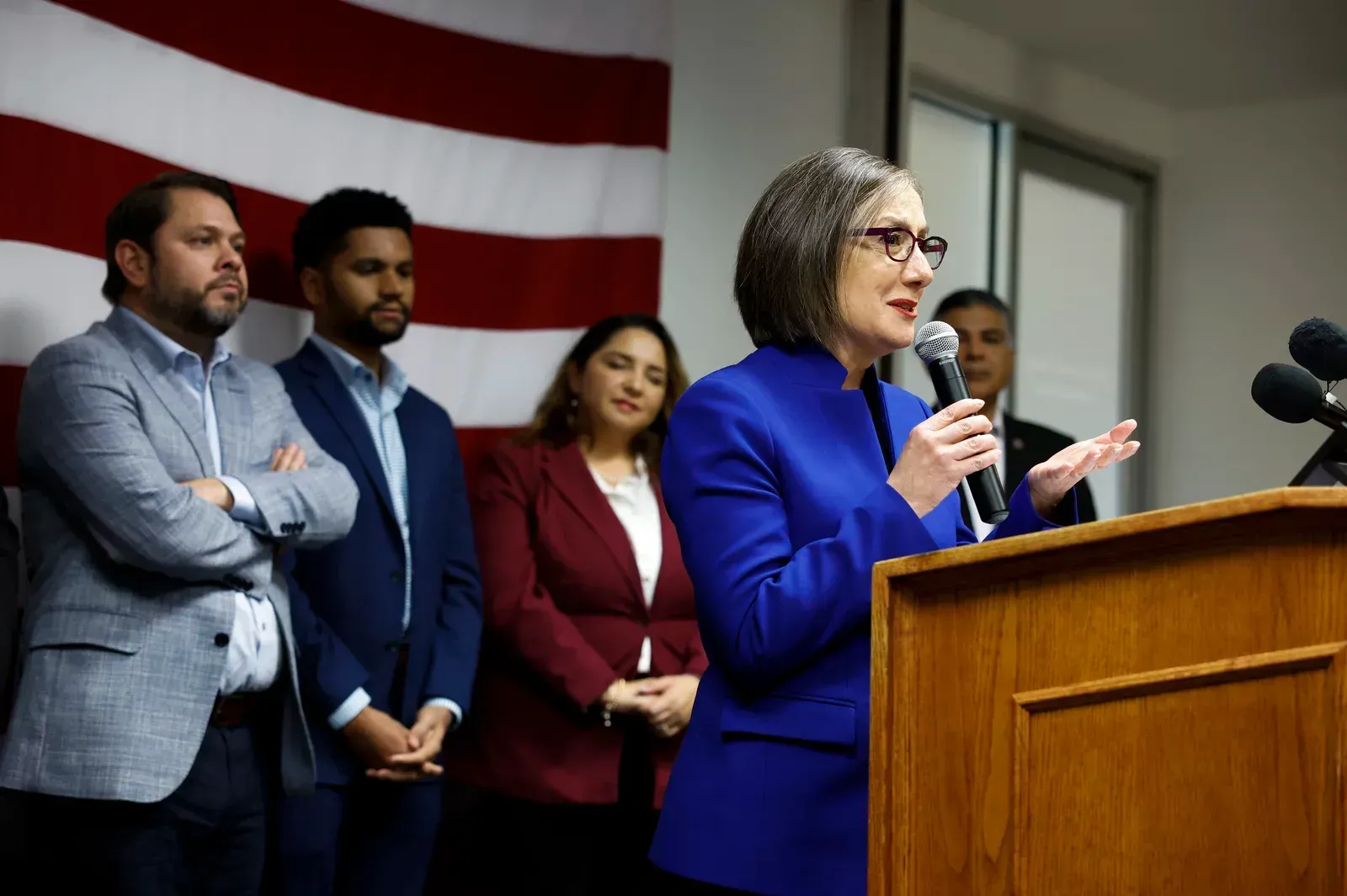 A woman is standing at a podium speaking into a microphone.