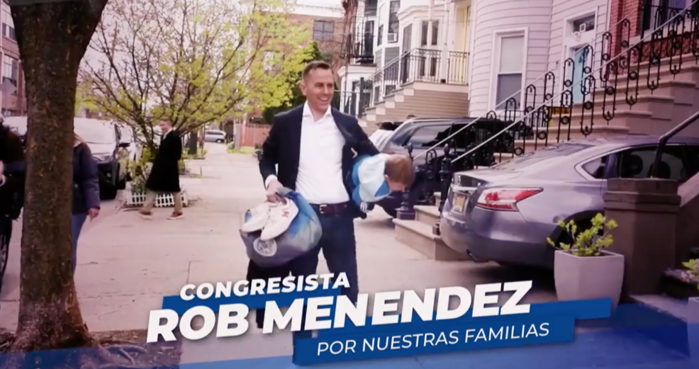 A man in a suit is standing on a sidewalk holding a bag of clothes.