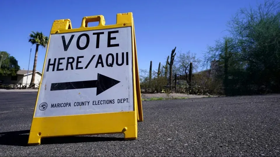 A yellow sign that says vote here / aqui on it