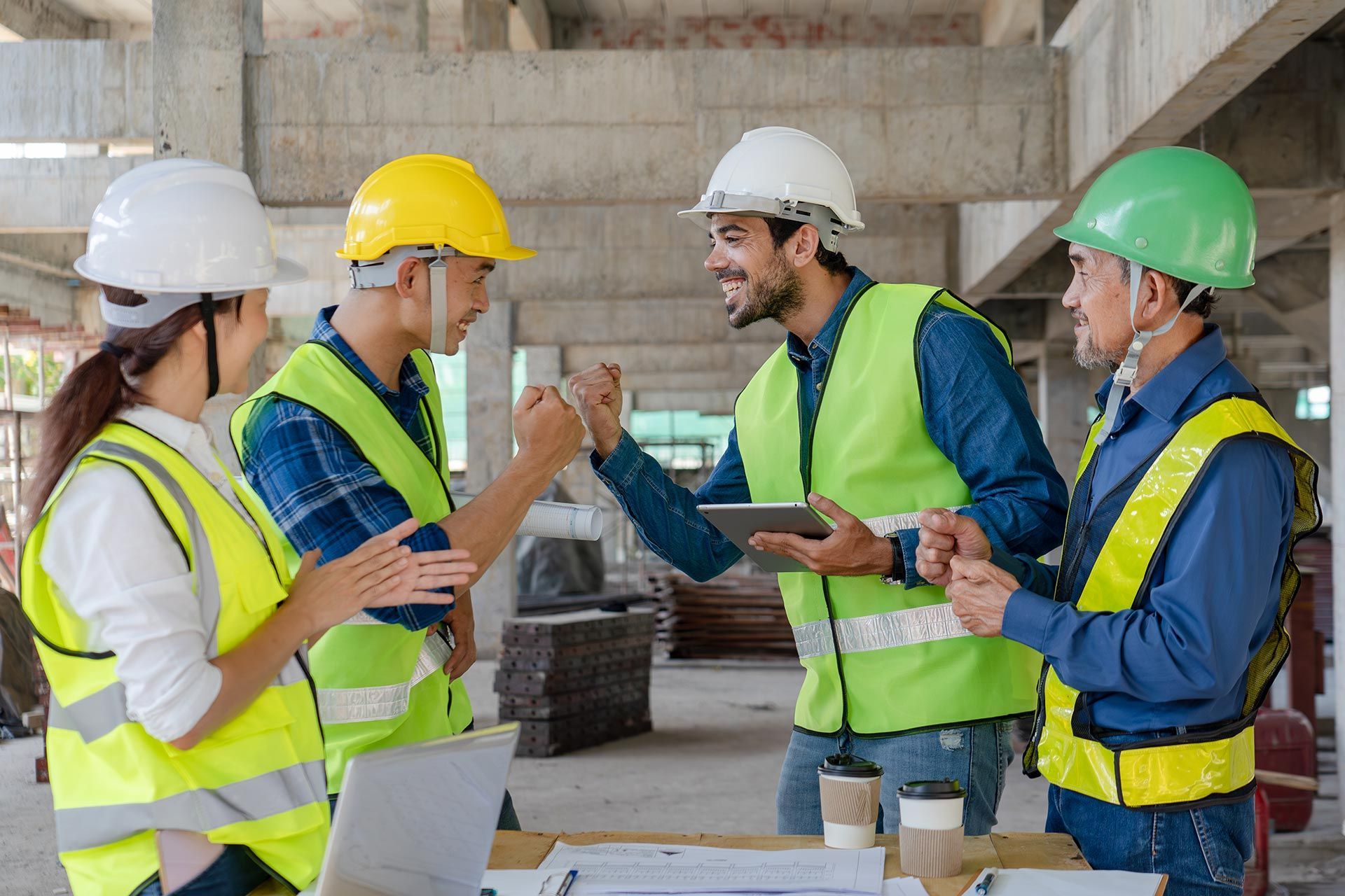 Construction team in hard hats and safety vests discussing plans at a building site.