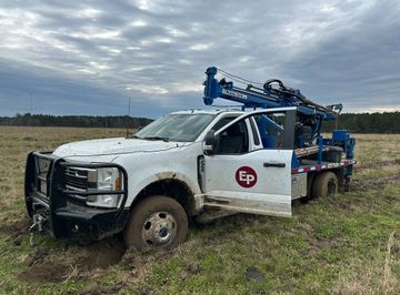 Geotechnical Engineering — Meridian, MS — Engineering Plus, Inc. Two men operating a drilling rig mounted on a truck in a field. Cloudy sky, roadside setting.