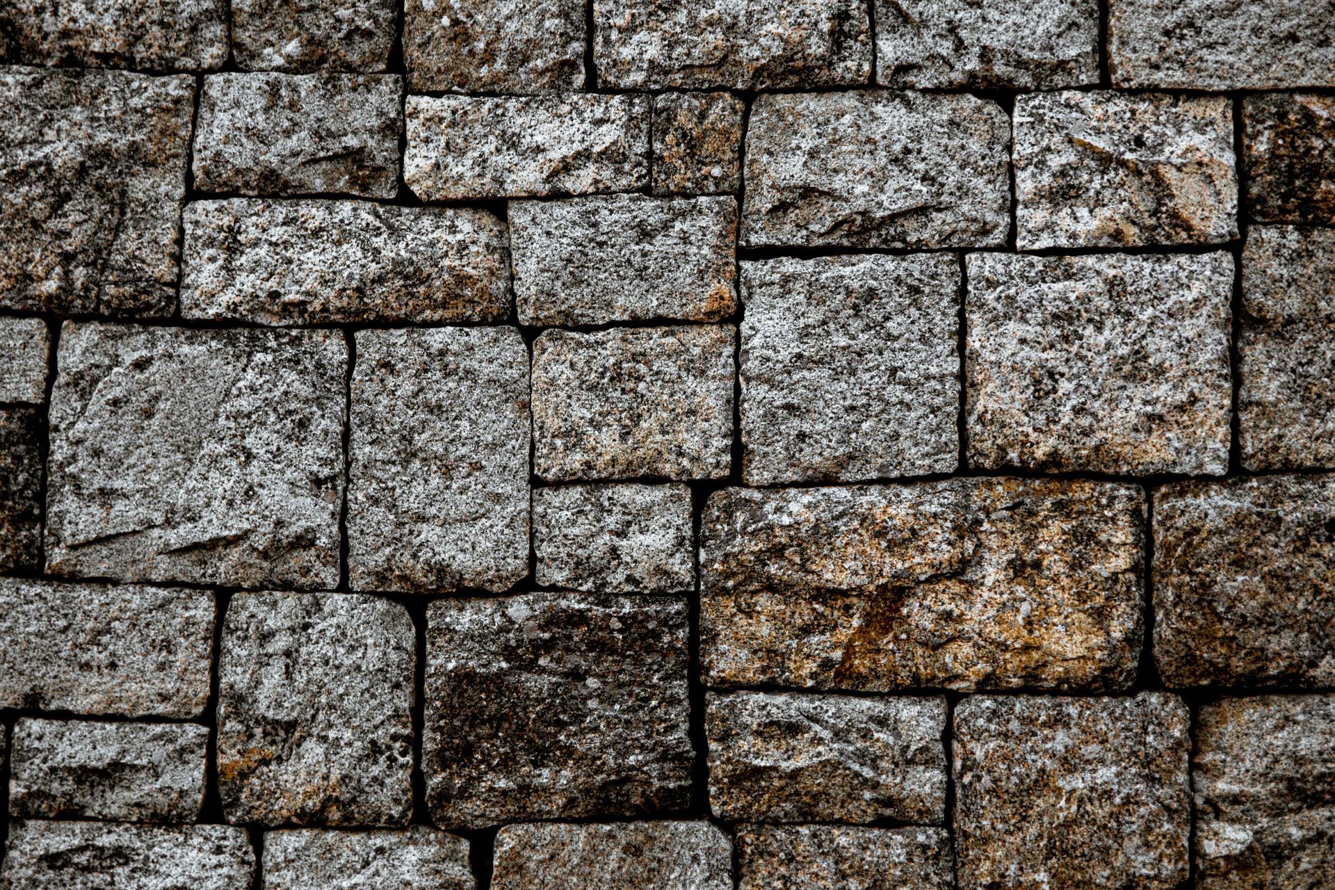 Close-up of a rough gray and brown stone wall with irregular stacked blocks