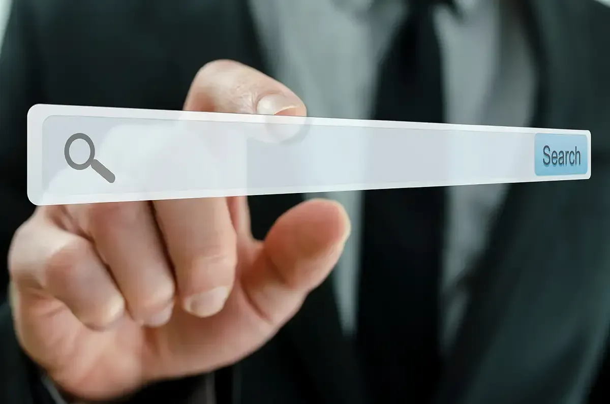 Person im Anzug hält eine transparente Suchleiste mit einem Lupensymbol.
