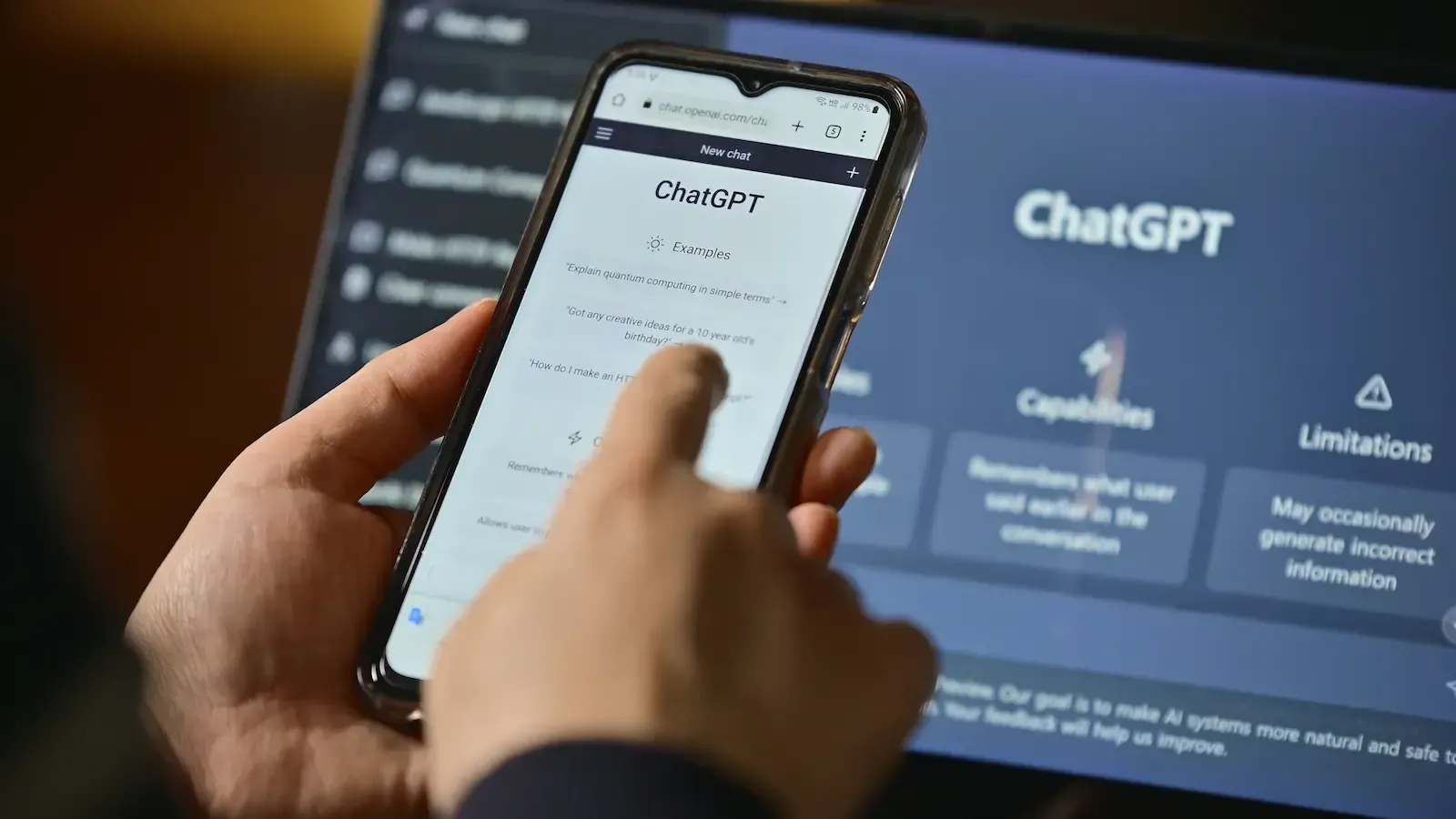 Eine Person nutzt ein Smartphone, um auf die ChatGPT-Oberfläche zuzugreifen, während im Hinterg