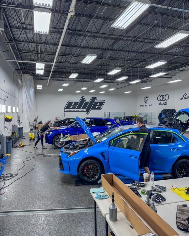 Bright auto shop with blue sports cars under maintenance and tools scattered around the floor