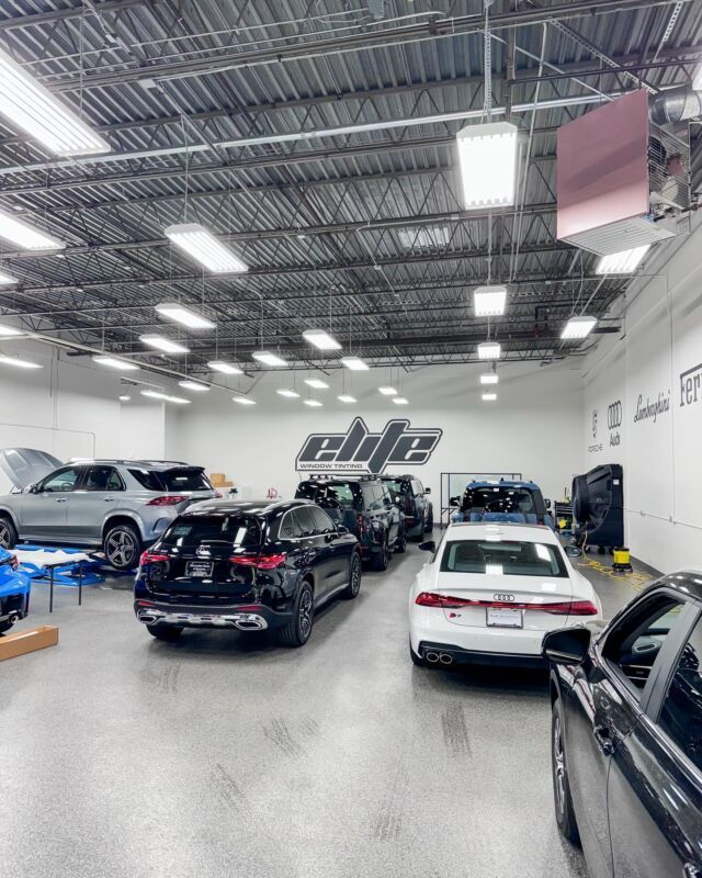 Car repair shop with several cars parked indoors under bright overhead lights