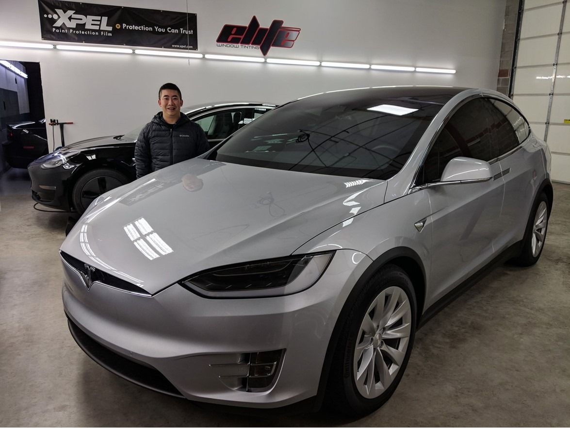 Silver Tesla SUV in a garage with a person standing beside it