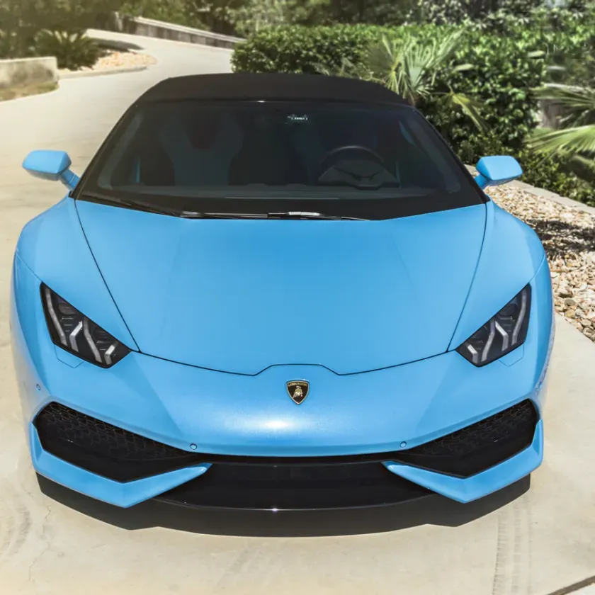Bright blue Lamborghini sports car viewed from the front, parked outdoors