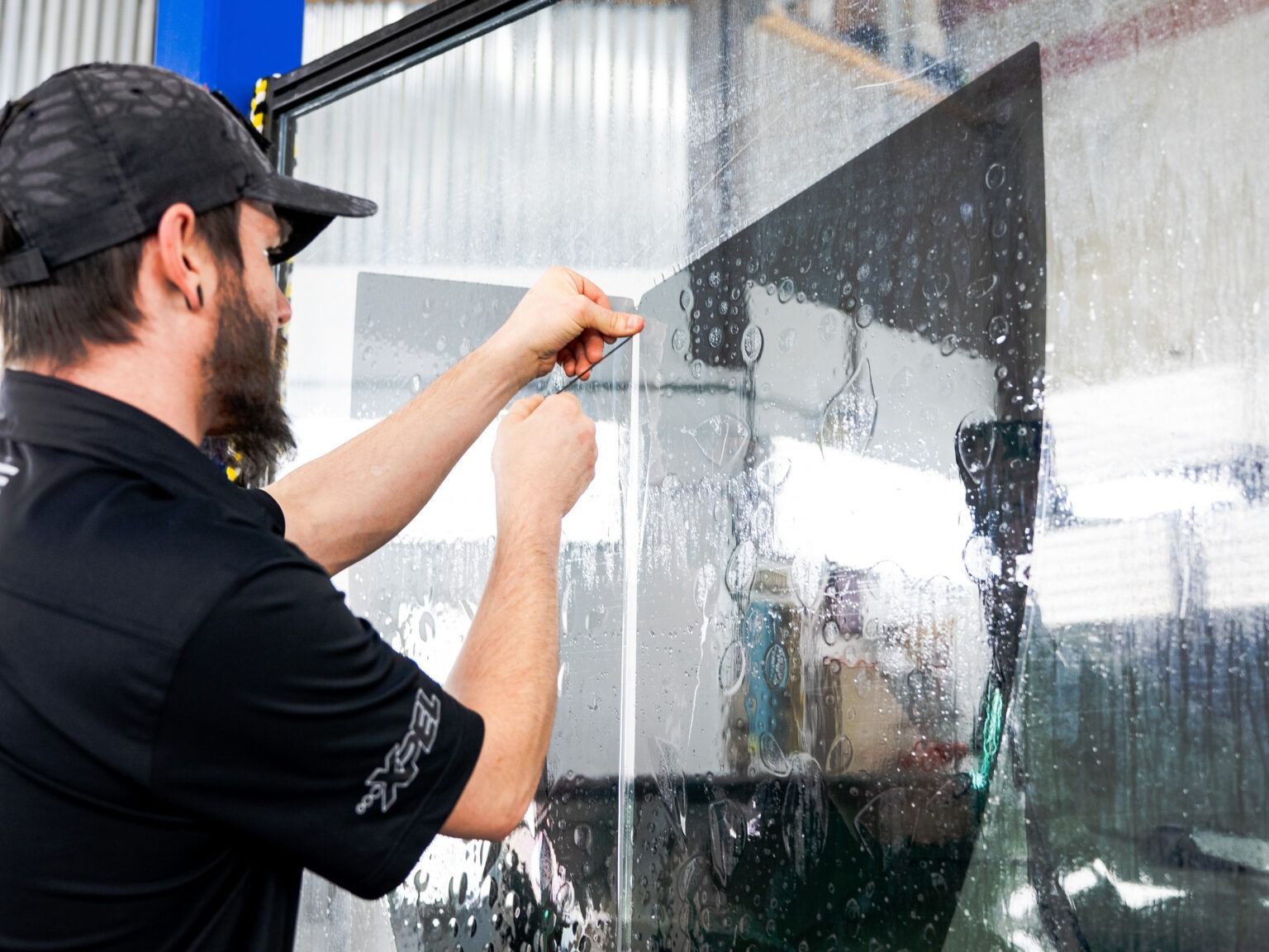 Man installing a large glass pane in a window frame indoors