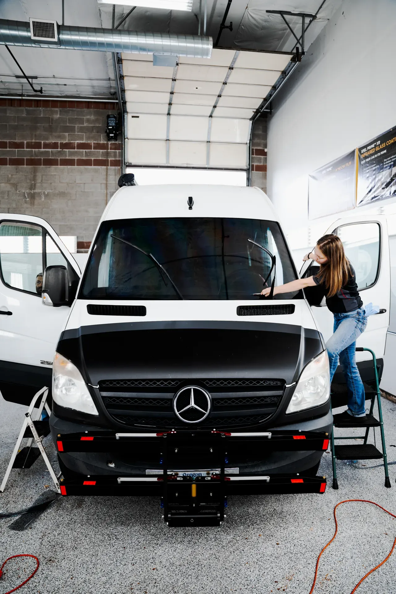 White Mercedes van in a garage, with a mechanic working at the open side door.