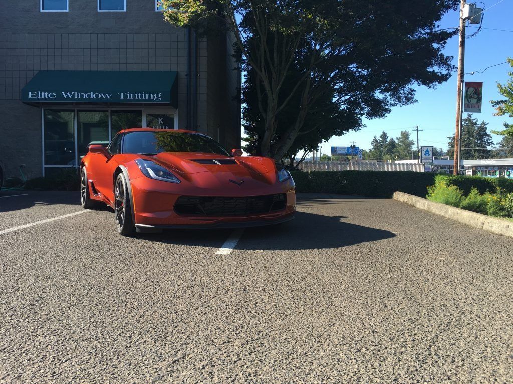 Red sports car parked outside a building on a sunny day.