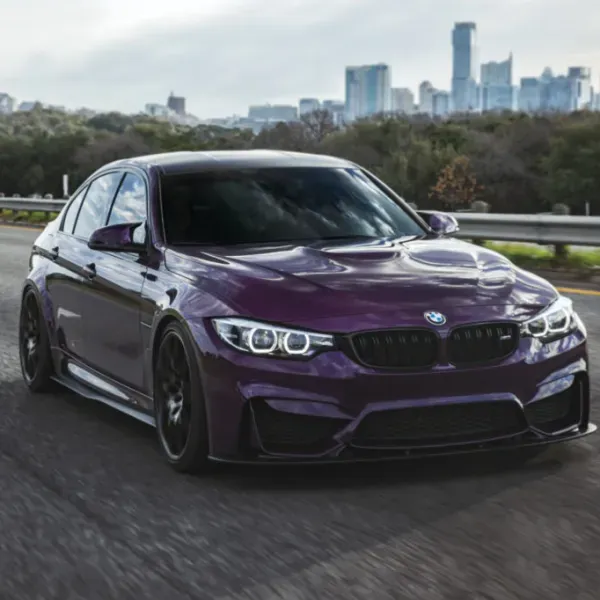 Purple BMW sedan driving on a road with a city skyline in the background