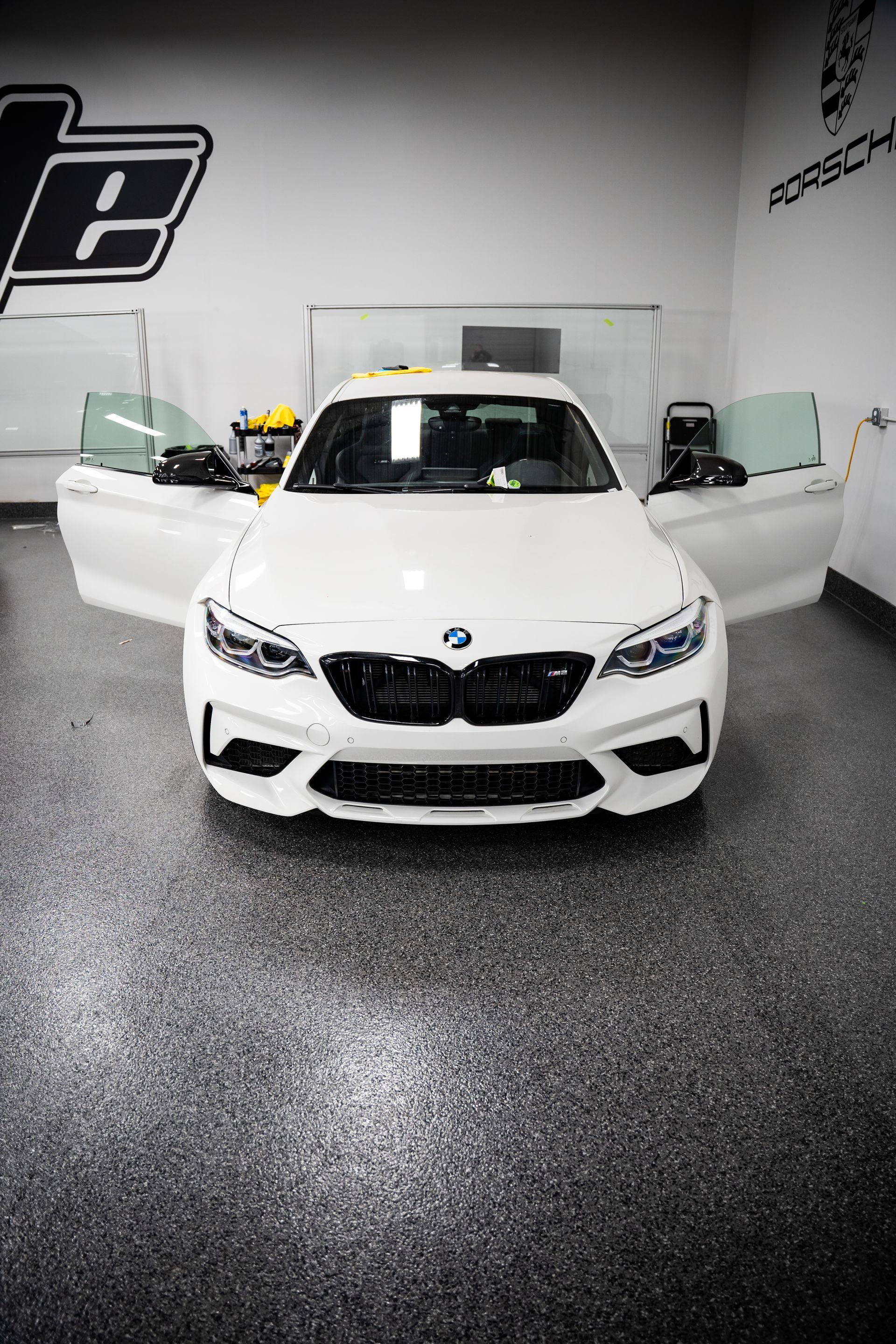 White BMW sedan with both front doors open in a garage showroom