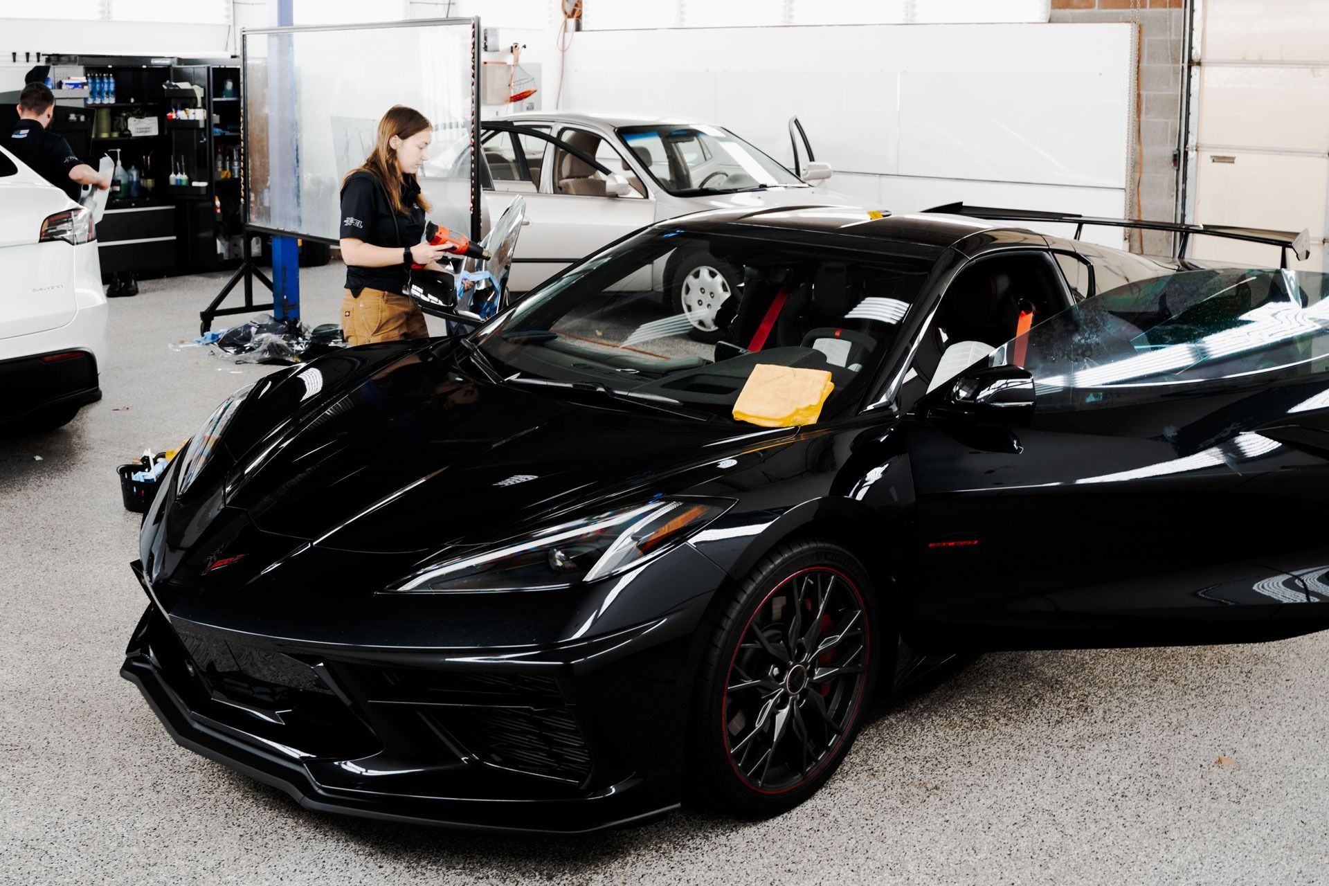 Black sports car in an auto showroom with a person standing nearby